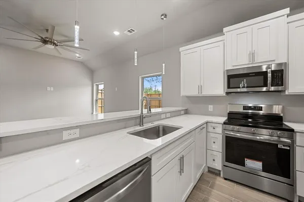 a kitchen with granite countertop a sink a stove and microwave