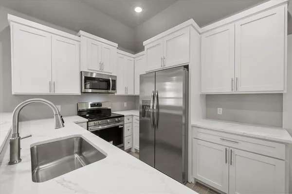 a kitchen with a refrigerator sink and white cabinets
