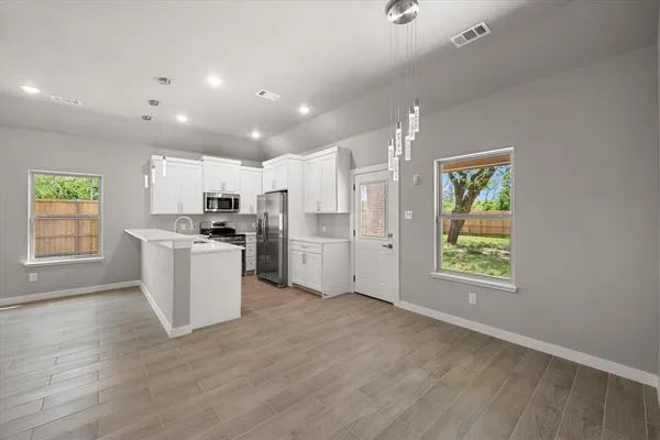 a view of kitchen with furniture a refrigerator and wooden floor