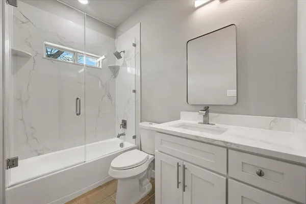 a bathroom with a granite countertop sink a toilet and shower