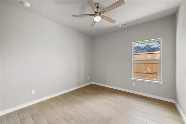 an empty room with a window and ceiling fan