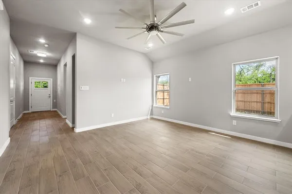 a view of an empty room with window and wooden floor