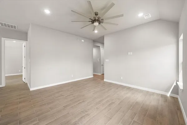 an empty room with wooden floor and fan