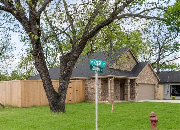 a front view of a house with a yard and large trees