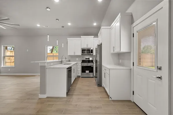 a kitchen with white cabinets and appliances