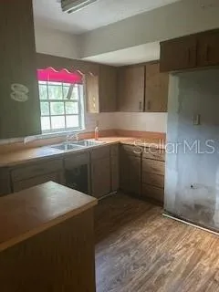 a kitchen with granite countertop a sink stainless steel appliances white cabinets and a window