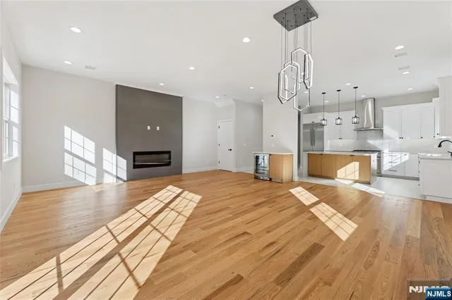 a large room with kitchen island stainless steel appliances wooden floor and living room view