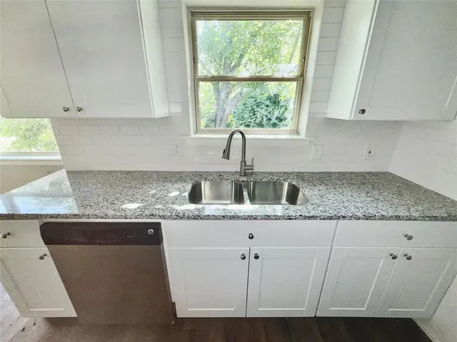 a kitchen with granite countertop a sink and a white cabinets