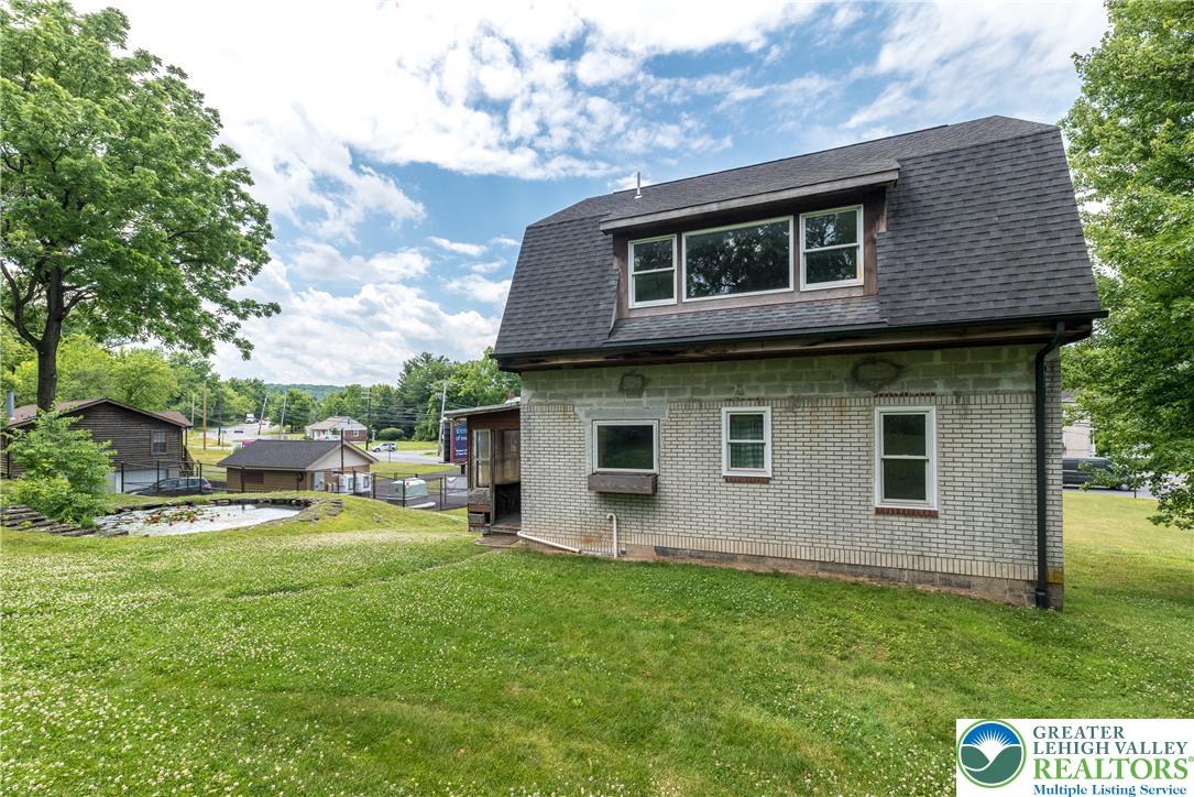 1815 Leithsville Road Hellertown, PA 18055 - Photo 32 of 38 A classic brick exterior combines with a well-maintained lawn, featuring a charming pond in the private yard.