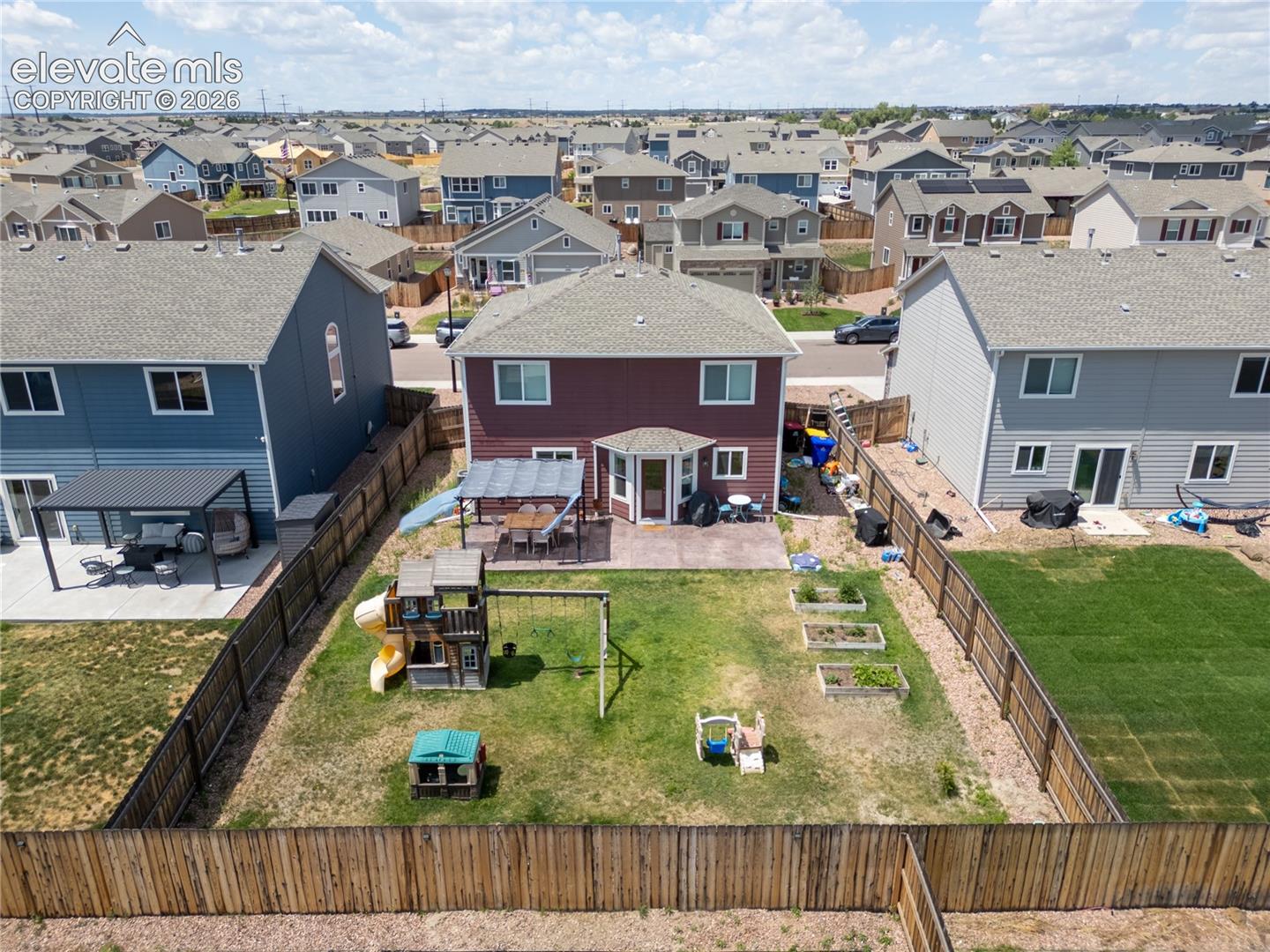 10993 Avena Road Peyton, CO 80831 - Photo 28 of 42 Spacious backyard featuring a wood privacy fence, concrete patio, and multiple raised garden beds