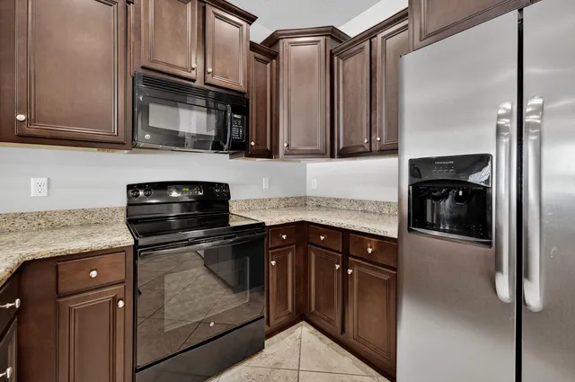 a kitchen with granite countertop a refrigerator stove and microwave