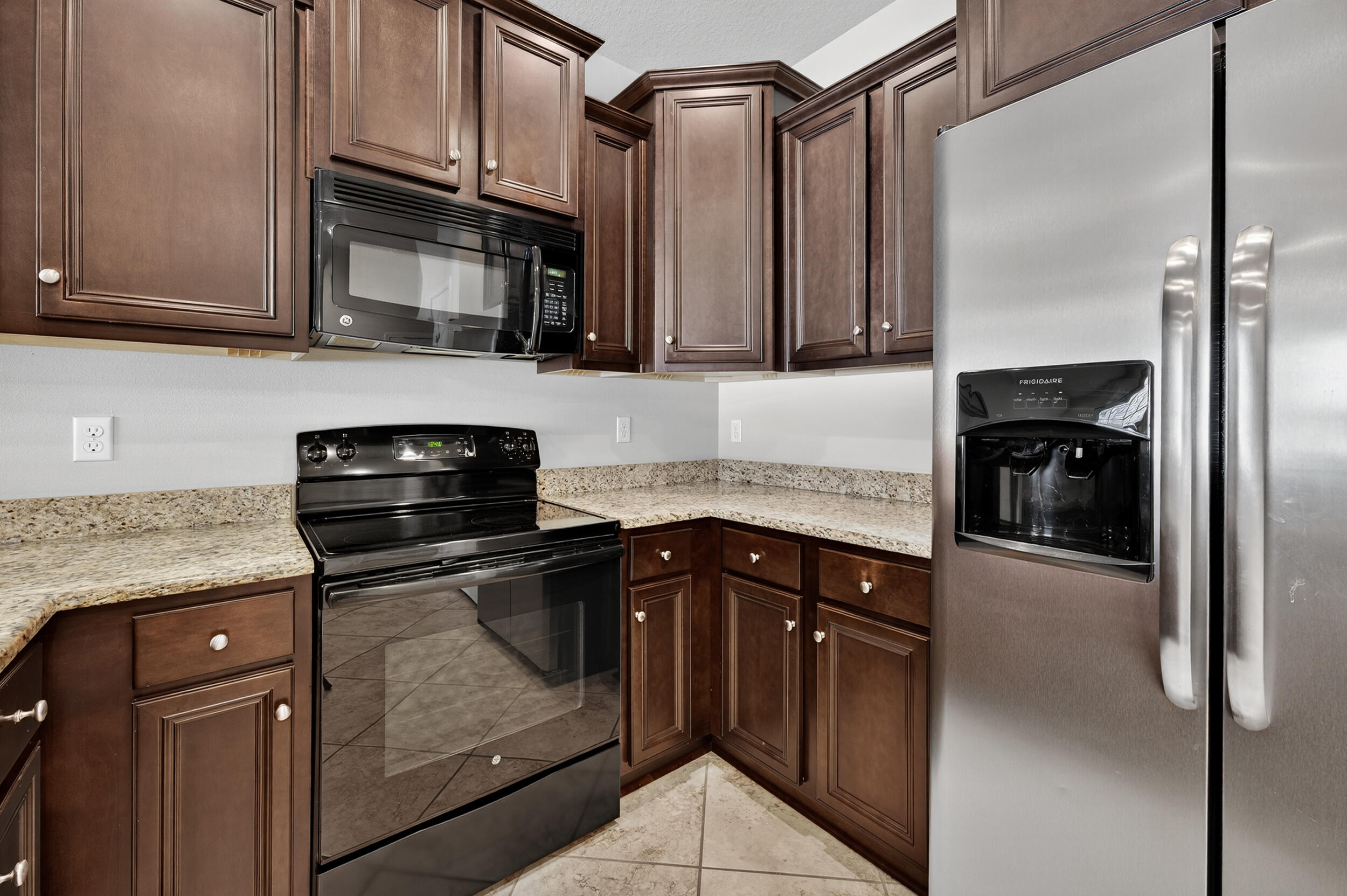 8900 White Ibis Way Navarre, FL 32566 - Photo 9 of 37 a kitchen with granite countertop a refrigerator stove and microwave