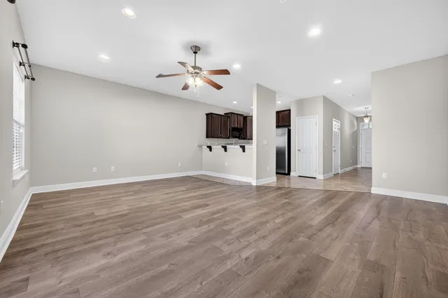 a view of empty room with wooden floor and ceiling fan