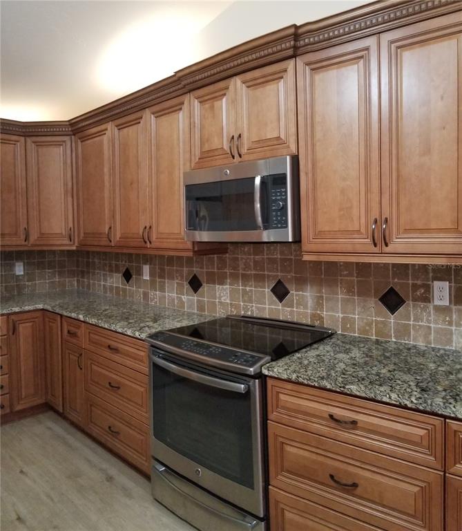 5810 Garden Lakes Majestic Bradenton, FL 34203 - Photo 3 of 28 a kitchen with stainless steel appliances granite countertop a stove a microwave and cabinets