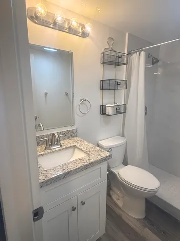 a bathroom with a granite countertop sink toilet and shower