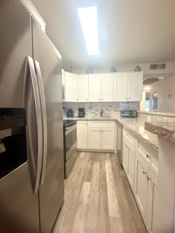 a large kitchen with stainless steel appliances granite countertop a stove a sink dishwasher and a refrigerator