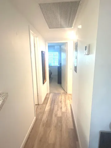 a view of a hallway with wooden floor and a bathroom