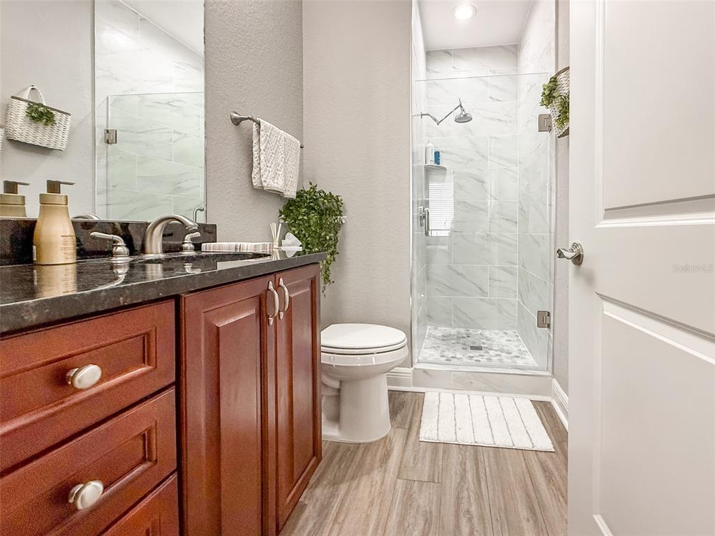 1038 Bellasol Way, Unit 202 Apollo Beach, FL 33572 - Photo 32 of 52 a bathroom with a granite countertop sink toilet a mirror and shower