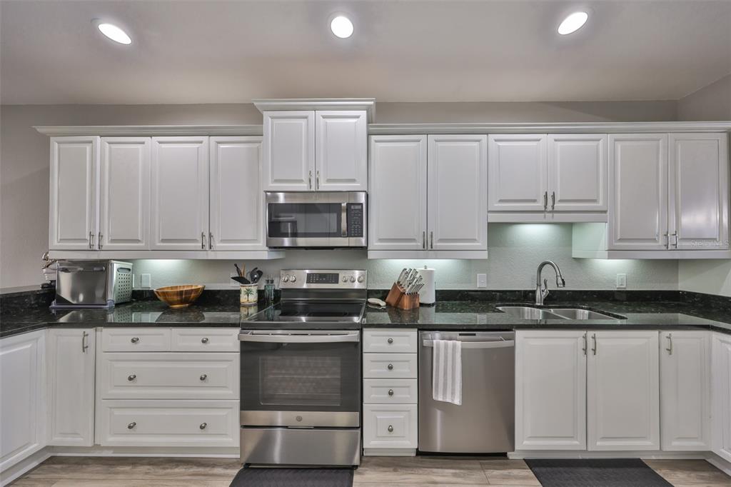 1038 Bellasol Way, Unit 202 Apollo Beach, FL 33572 - Photo 8 of 52 a kitchen with granite countertop white cabinets and stainless steel appliances