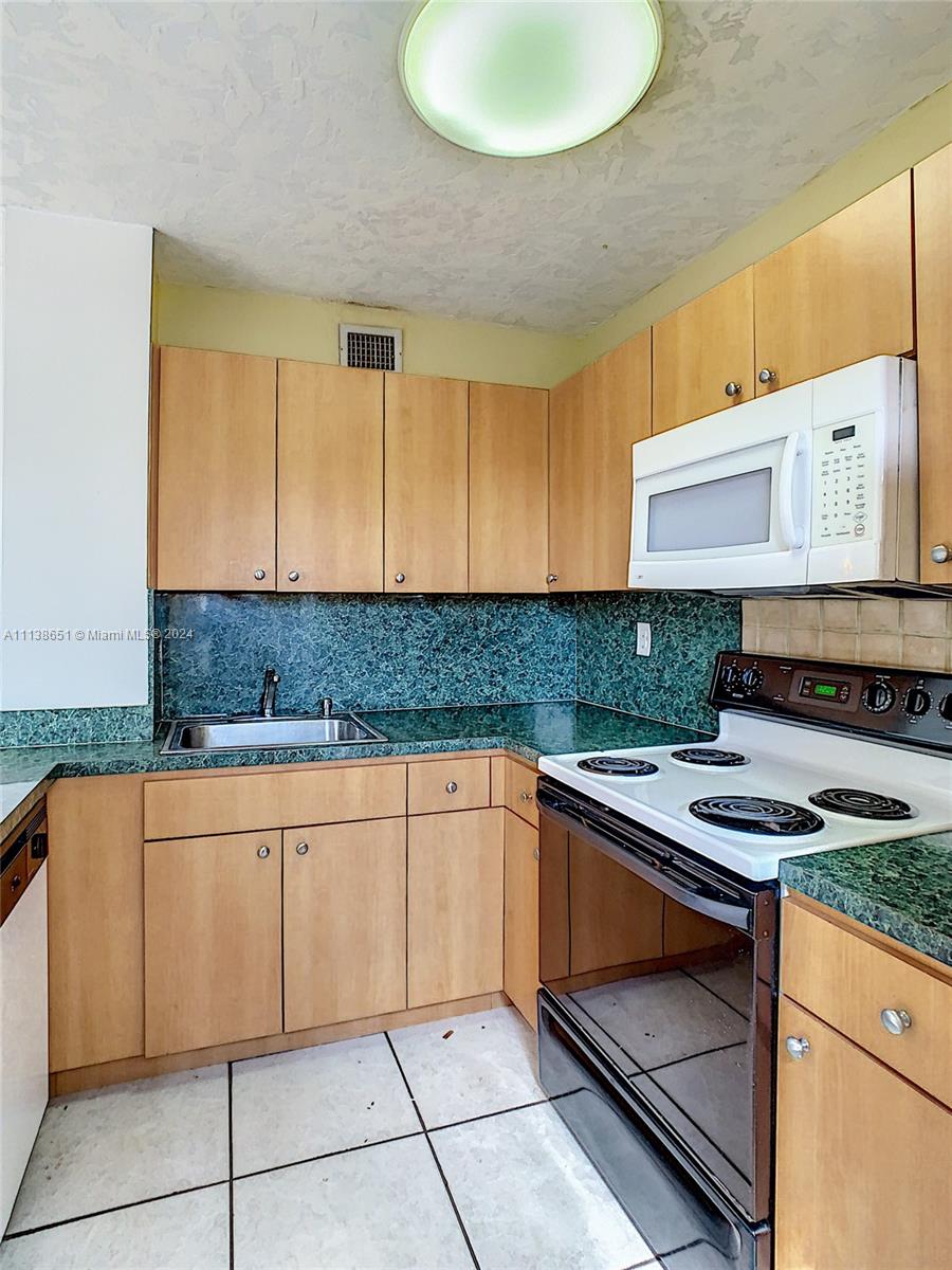 6445 Indian Creek Drive, Unit B16 Miami Beach, FL 33141 - Photo 3 of 18 a kitchen with stainless steel appliances granite countertop a stove sink and cabinets