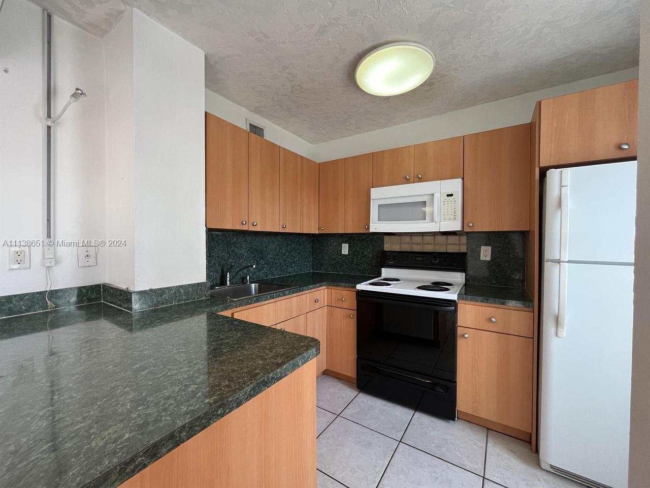 6445 Indian Creek Drive, Unit B16 Miami Beach, FL 33141 - Photo 5 of 18 a kitchen with granite countertop a stove a refrigerator and a sink