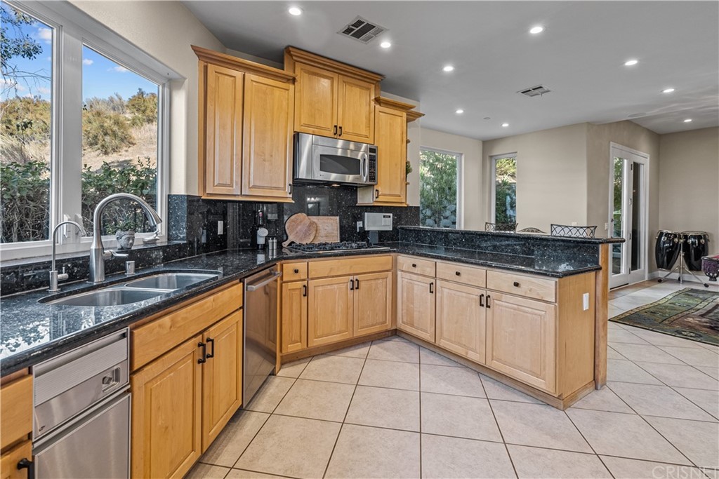 24806 Carlos Place Newhall, CA 91321 - Photo 15 of 44 a large kitchen with granite countertop a sink and white cabinets