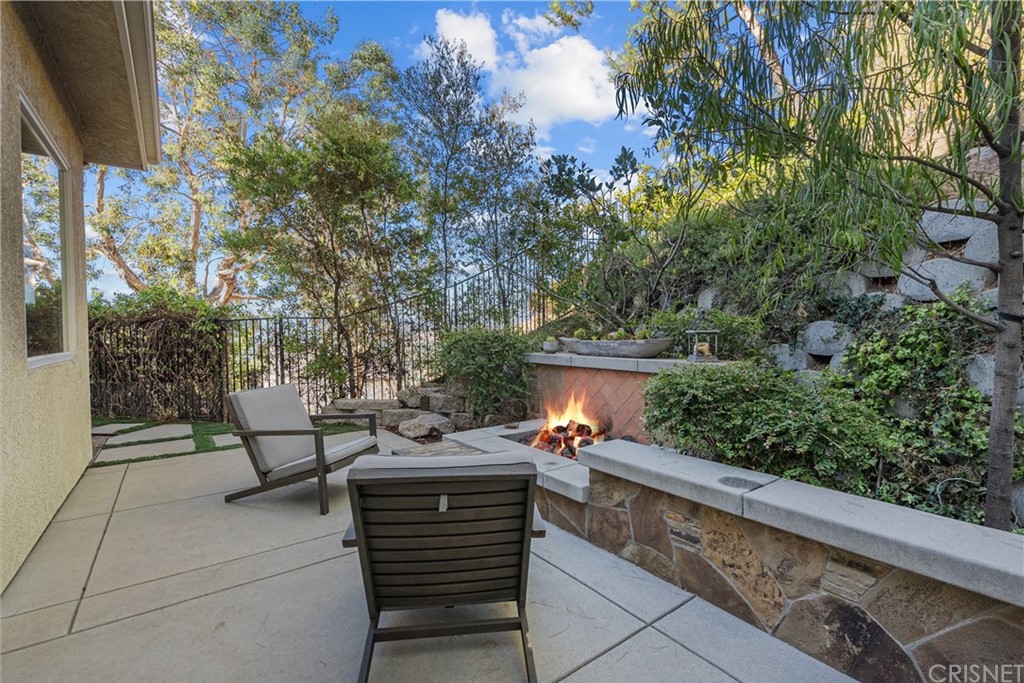 24806 Carlos Place Newhall, CA 91321 - Photo 17 of 44 a wooden bench sitting in backside of a house with potted plants and large trees