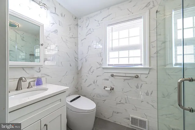 a bathroom with a granite countertop toilet a sink a mirror and shower