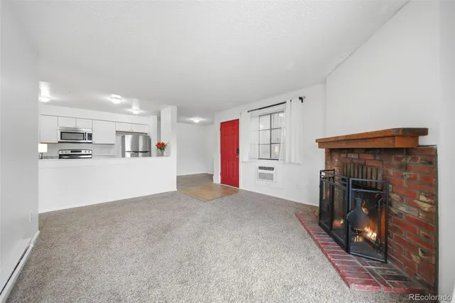 a view of empty room with kitchen and fireplace