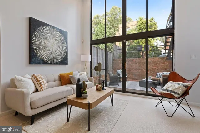 a living room with furniture a fireplace and a floor to ceiling window