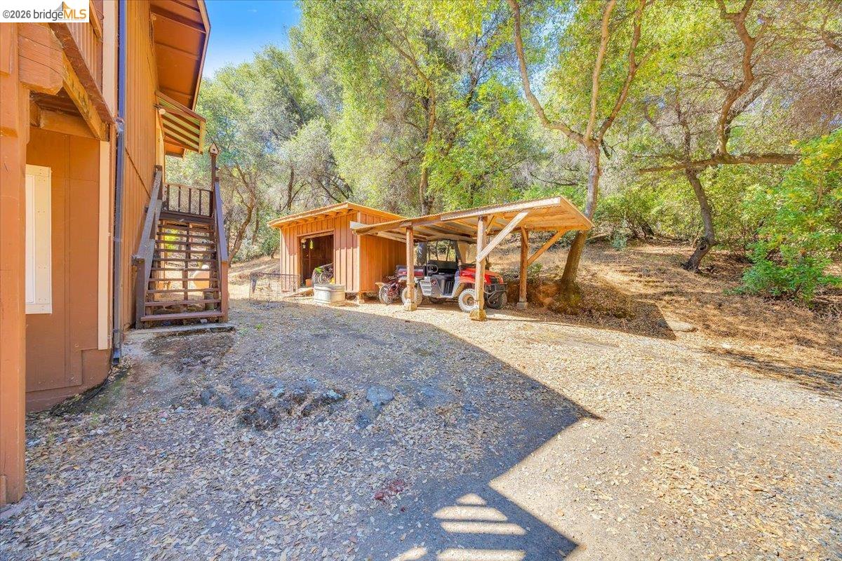 8733 Fraguero Road Sonora, CA 95370 - Photo 68 of 73 Gravel driveway with a detached shed, a separate carport, and an exterior staircase leading to the upper level of the residence