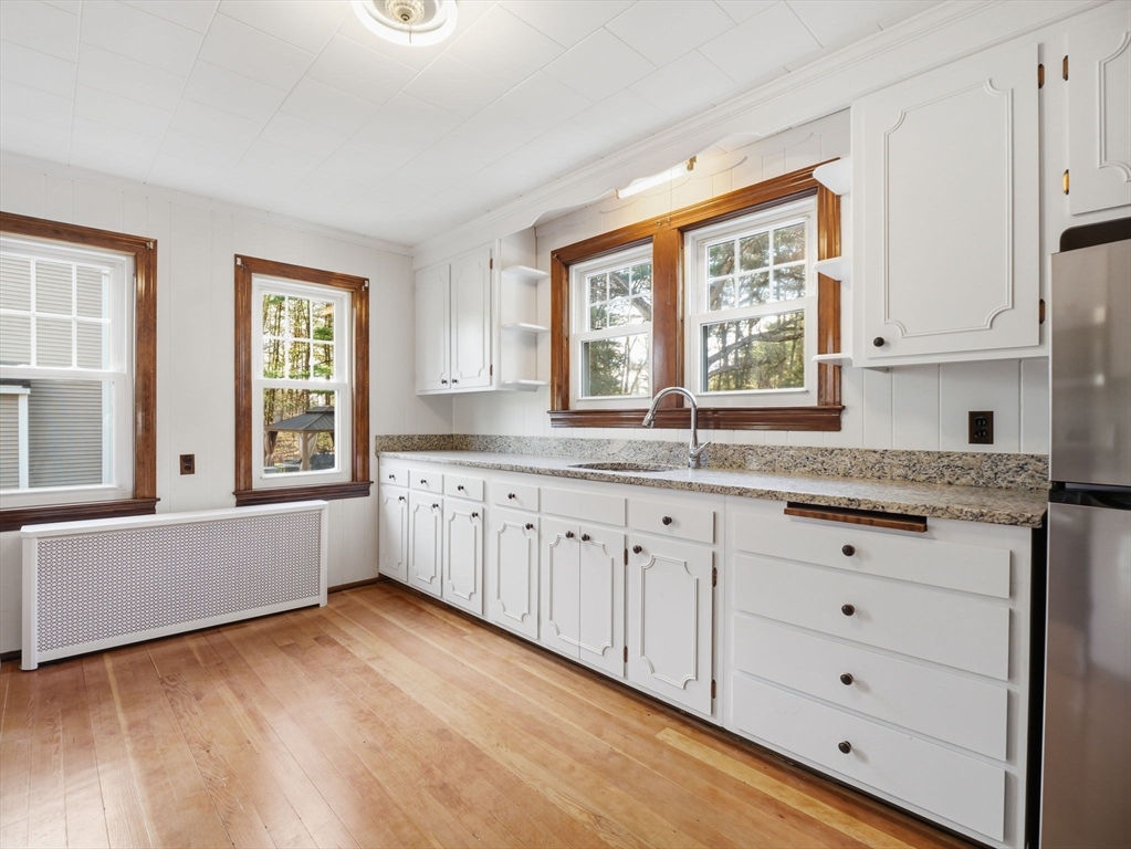 285 West Meadow Road Lowell, MA 01854 - Photo 6 of 32 a kitchen with granite countertop a stove a sink and white cabinets with wooden floor