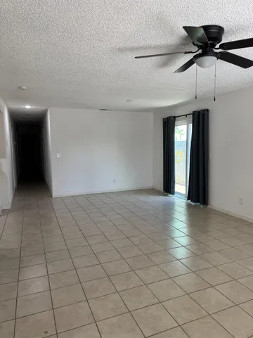an empty room with ceiling fan and window