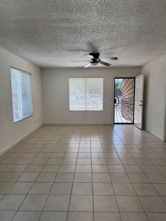 an empty room with windows and fan