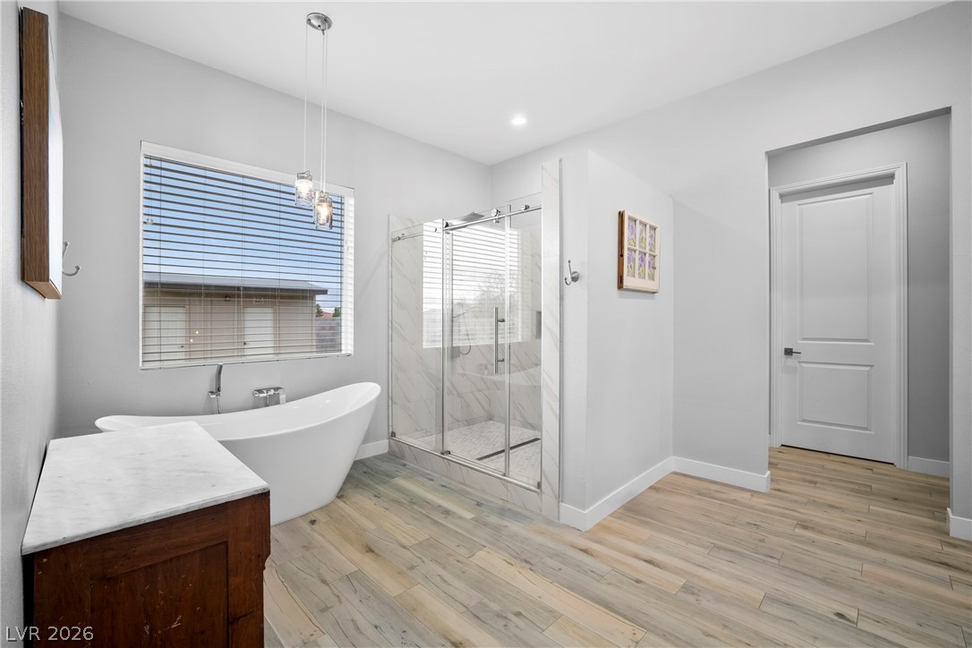 432 North Racetrack Road Henderson, NV 89015 - Photo 22 of 45 Bathroom featuring a marble finish shower, a freestanding tub, and light wood-type flooring