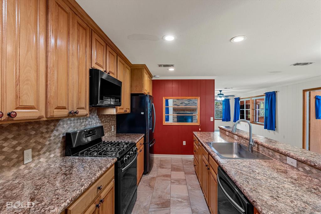 225 Marie Road Ringgold, LA 71068 - Photo 31 of 40 Kitchen featuring wood cabinetry, integrated black appliances, a gas range, a multi-tone tile backsplash, and composite countertops