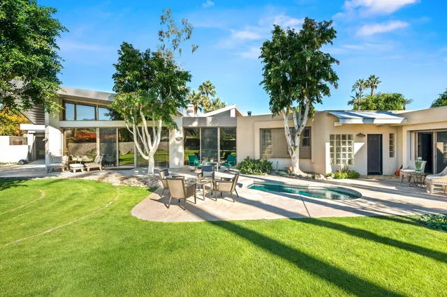 a view of a patio with couches table and chairs potted plants and palm tree