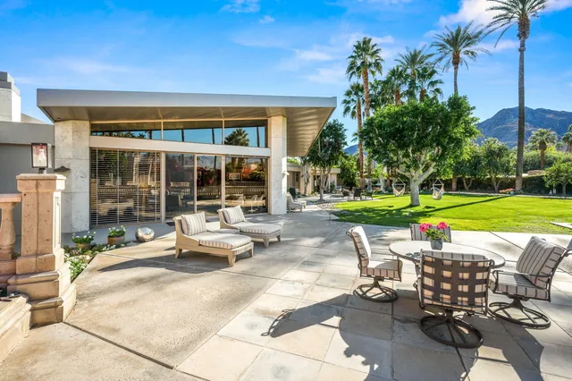a view of a patio with table and chairs potted plants and palm trees