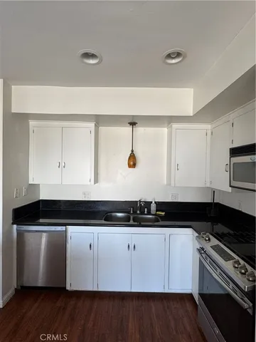 a white kitchen with granite countertop a sink and a stove
