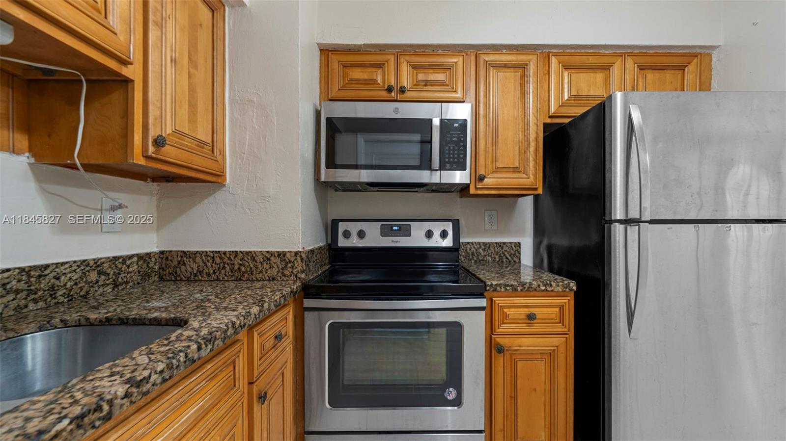 1235 Northwest 86th Street Miami, FL 33147 - Photo 17 of 37 a kitchen with granite countertop a sink stove and refrigerator