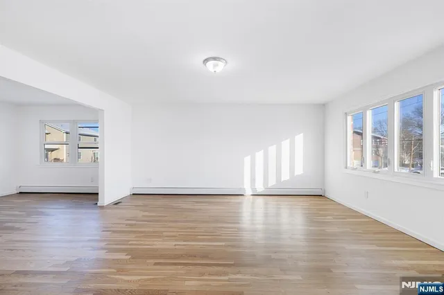 a view of an empty room with a window and wooden floor
