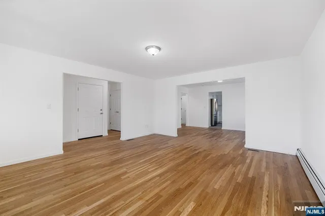 a view of an empty room with wooden floor and closet