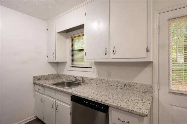a kitchen with granite countertop white cabinets and a sink