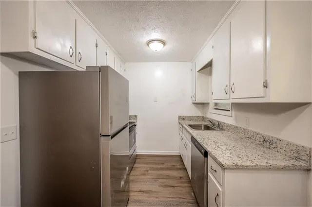 a kitchen with stainless steel appliances granite countertop white cabinets and refrigerator