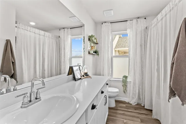 a bathroom with double vanity sink a toilet and a large mirror