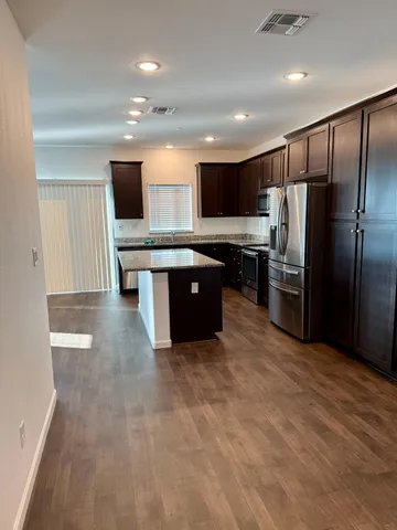 a large kitchen with stainless steel appliances a stove a sink and a refrigerator