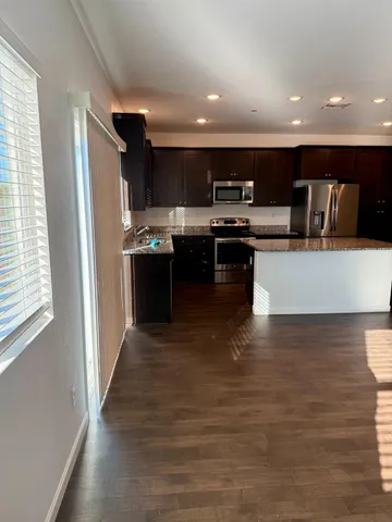 a kitchen with stainless steel appliances kitchen island granite countertop a stove a sink and a refrigerator