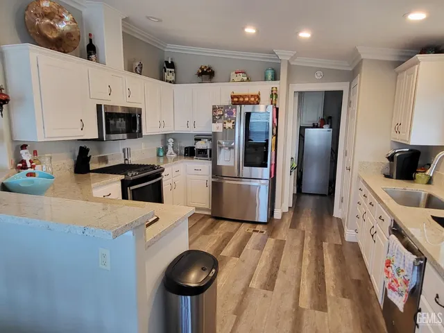 a kitchen with granite countertop a sink a stove top oven a refrigerator and cabinets