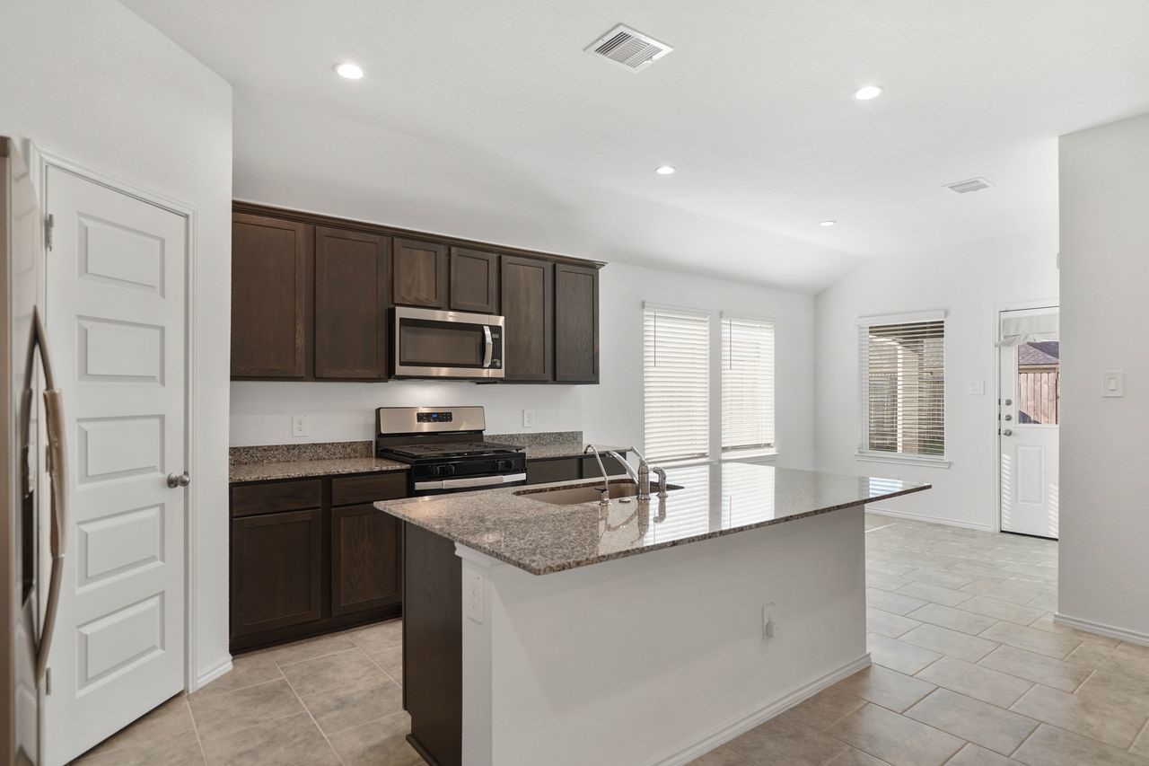7502 Fierce Friesian Lane Rosharon, TX 77583 - Photo 5 of 21 a kitchen with granite countertop a refrigerator stove top oven and sink