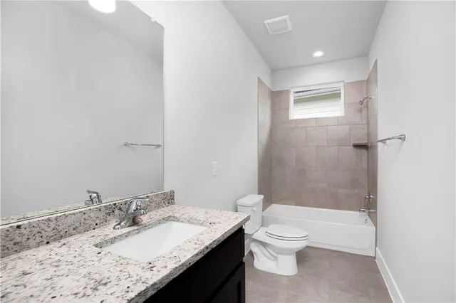 a bathroom with a granite countertop sink a toilet and shower